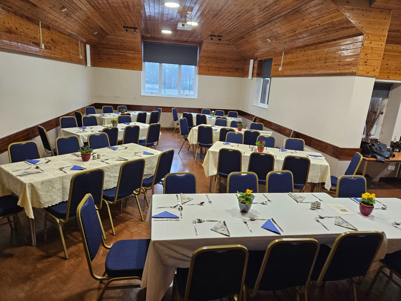Main hall arranged for a sit-down meal A well-arranged dining hall with tables set for a formal event.