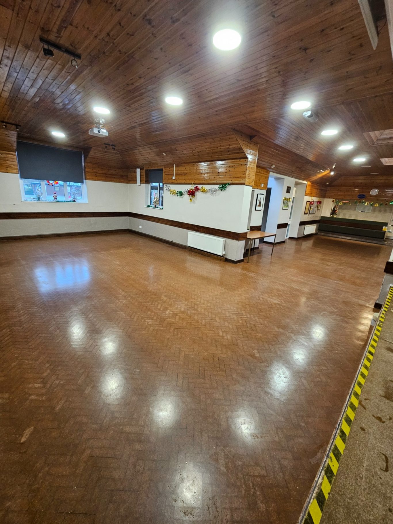 The main hall Spacious, well-lit interior of a hall with wooden walls and a polished floor.