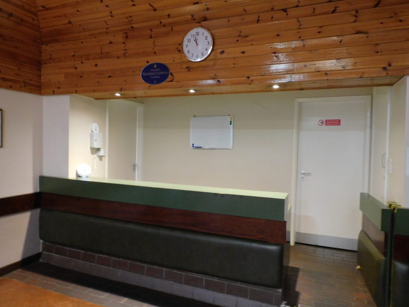 Bar Reception area with a wooden ceiling, clock, and a green and brown counter.